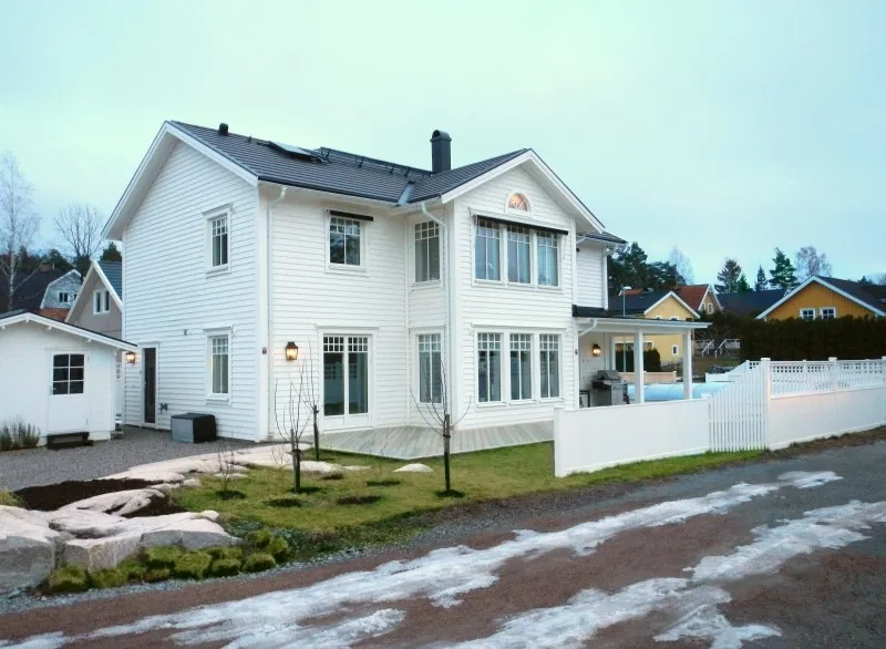 Vit villa med staket på en nyanlagd tomt